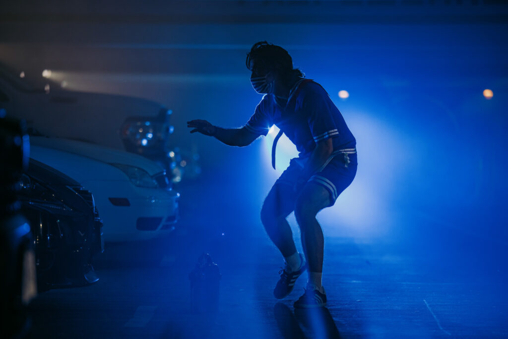 Silhouette of a male character at the Stranger Things Drive-Into Experience interacting with guests in cars with a bright blue spotlight behind him